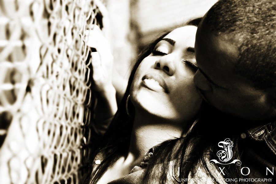 Sexy photo of couple kissing against a chain-link fence