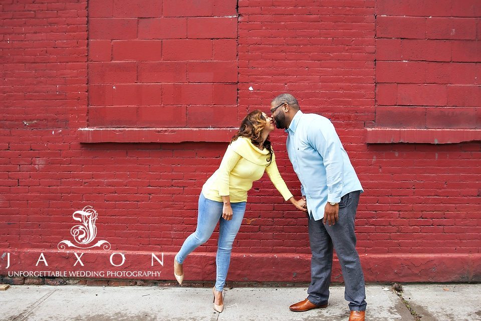 Couple kisses against a backdrop of red brick wall