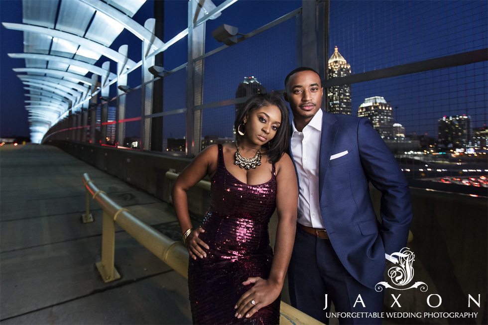 Beautifully dressed young couple he is in a blue suite and she is wearing a metallic spaghetti strap plum dress, adding some sophistication on 17th St Bridge in Atlantic Station Atlanta